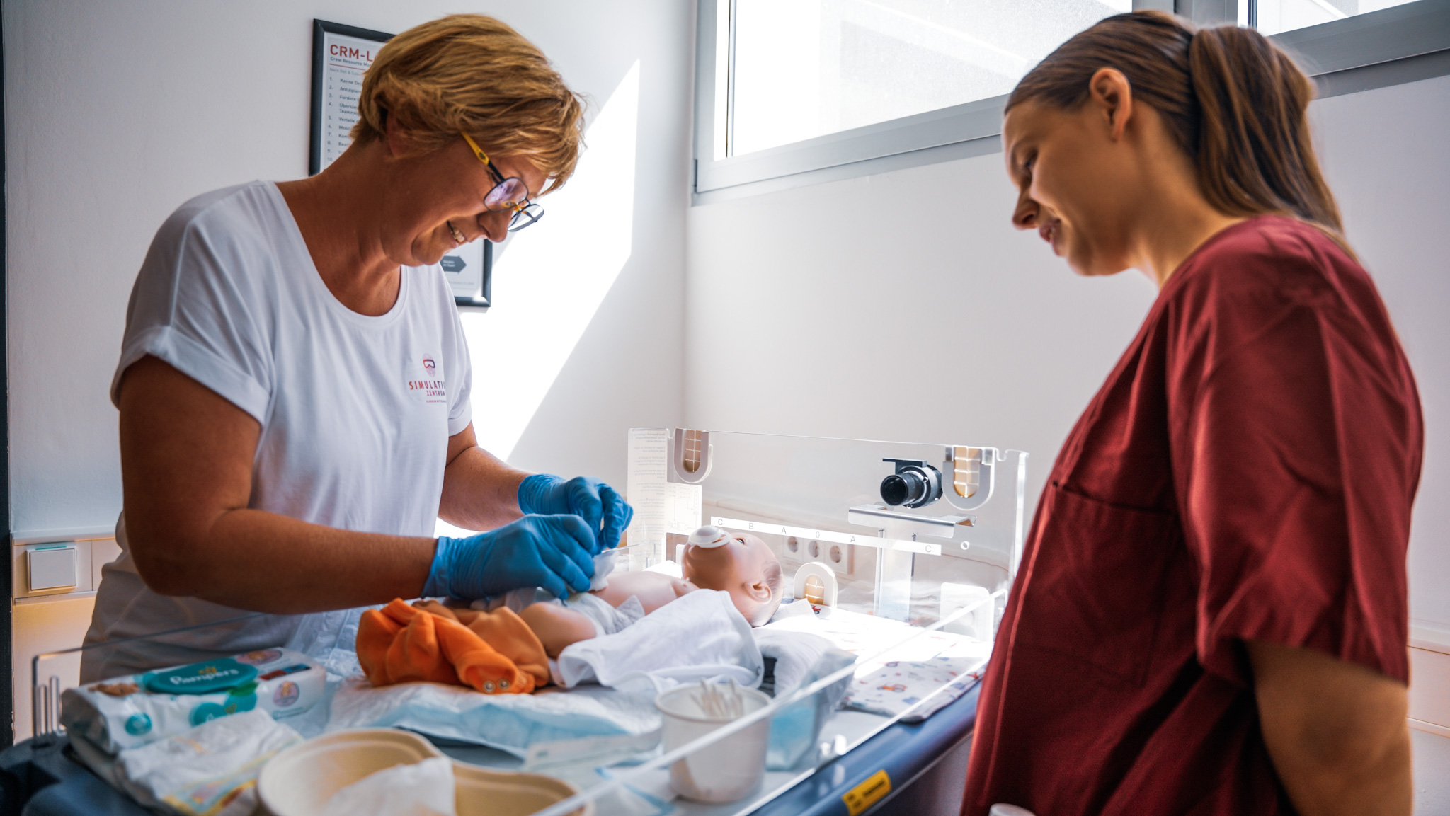 zwei Personen stehen an einem Inkubator und pflegen das Baby